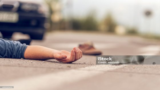 Car hit scene, male person lying on the floor in front of a car