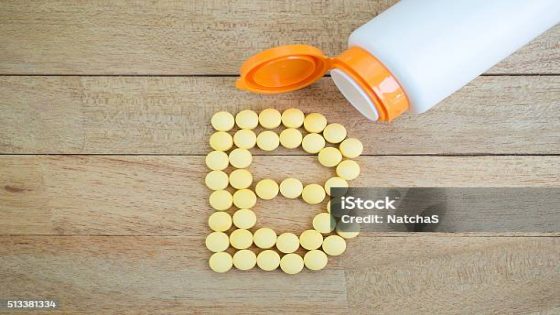 Yellow pills forming shape to B alphabet on wood background