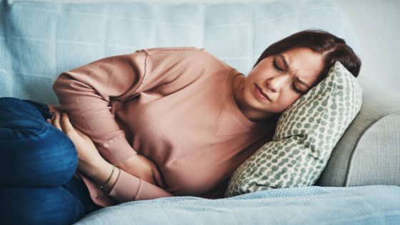 Shot of a young woman experiencing stomach pain while lying on the sofa at home